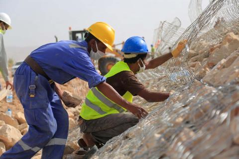 Workers construct a gabion wall in Al Jufainah displacement site to protect families from torrential rains. © IOM 2021/ Elham Al Oqabi